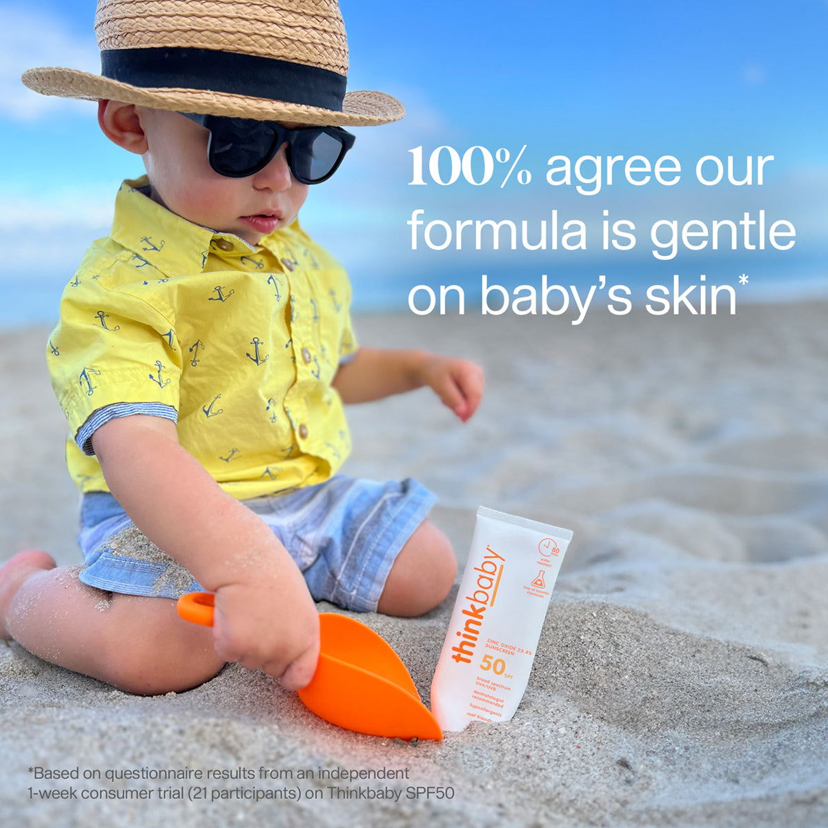 A toddler on a beach, wearing a hat and sunglasses, sitting next to a Thinkbaby sunscreen tube with text stating "100% agree it's gentle on baby’s skin".
