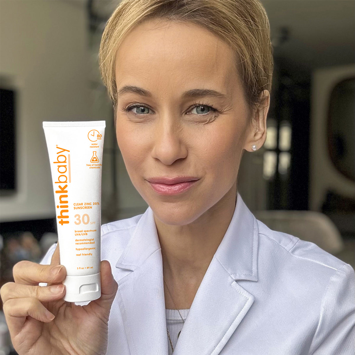 Person holding ThinkBaby Clear Zinc 30 SPF Sunscreen, highlighting its broad-spectrum UV protection and hypoallergenic, reef-friendly formula.