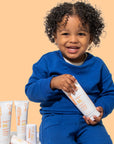 Smiling child holding ThinkBaby Clear Zinc 30 SPF Sunscreen, emphasizing safe and effective sun protection for kids.